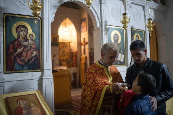 Priest Abuna Mata gives the communion during the Christmas mass in the Greek Orthodox convent Saint Takla, in Maaloula, some 60 km northern Damascus, Syria, Tuesday, Dec. 24, 2024. (AP Photo/Leo Correa)