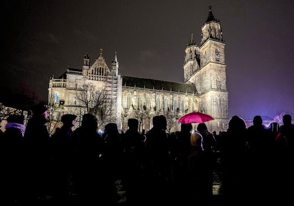 People attend a memorial service outside the cathedral close to the Christmas market, where a car drove into a crowd on Friday evening, in Magdeburg, Germany, Saturday, Dec. 21, 2024. (AP Photo/Michael Probst)