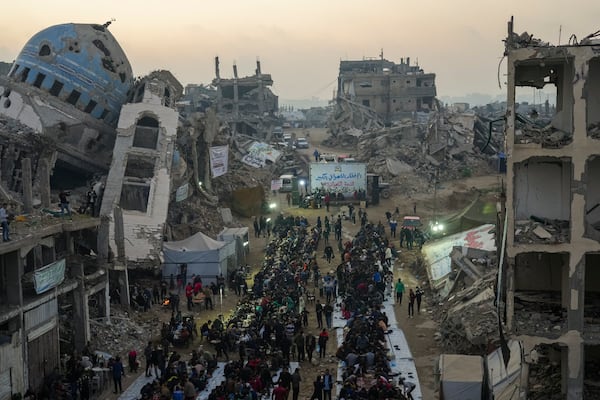 Surrounded by destroyed homes and buildings, Palestinians gather for iftar, the fast-breaking meal during Ramadan in Beit Lahia, northern Gaza Strip, Saturday, March 15, 2025. (AP Photo/Jehad Alshrafi)