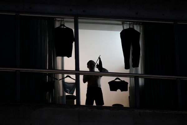 A migrant deported from the United States hangs clothes on a window in a hotel room in Panama City, Thursday, Feb. 20, 2025. (AP Photo/Matias Delacroix)