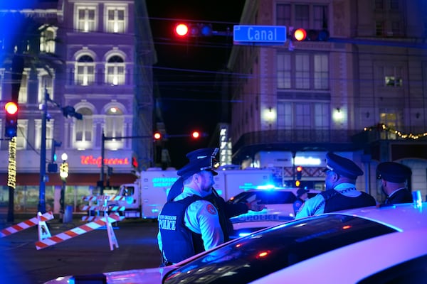 Police officers stand near the scene where a vehicle drove into a crowd on New Orleans' Canal and Bourbon streets, Wednesday, Jan. 1, 2025. (AP Photo/George Walker IV)