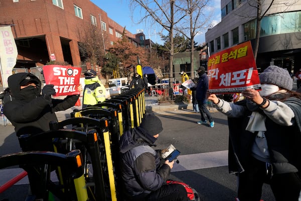 Demonstrators supporting, left, and opposing impeached South Korean President Yoon Suk Yeol confront each other near the presidential residence in Seoul, South Korea, Wednesday, Jan. 8, 2025. The letters on right read "Arrest Yoon Suk Yeol." (AP Photo/Ahn Young-joon)