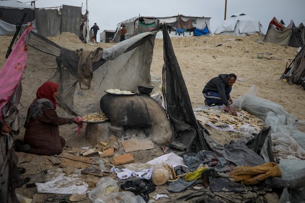 Mona Al-Zebda, displaced from Gaza City, bakes bread at a tent camp for displaced Palestinians at the Muwasi, Rafah, southern Gaza Strip, Monday, Feb. 24, 2025. (AP Photo/Jehad Alshrafi)