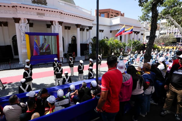 Government supporters and military guard listen to Venezuelan President Nicolas Maduro speak after his swearing-in ceremony for a third term as they watch a live video of him on a screen outside the National Assembly in Caracas, Venezuela, Friday, Jan. 10, 2025. (AP Photo/Matias Delacroix)