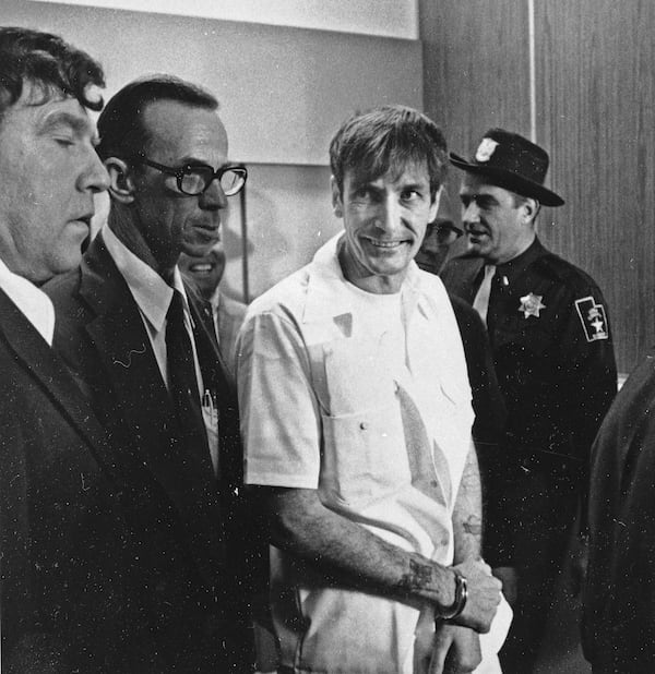 FILE - Convicted murderer Gary Mark Gilmore arrives, heavily guarded, at the 4th District Court in Provo, Utah, on Dec. 1, 1976. (AP Photo/Ron Barker, File)