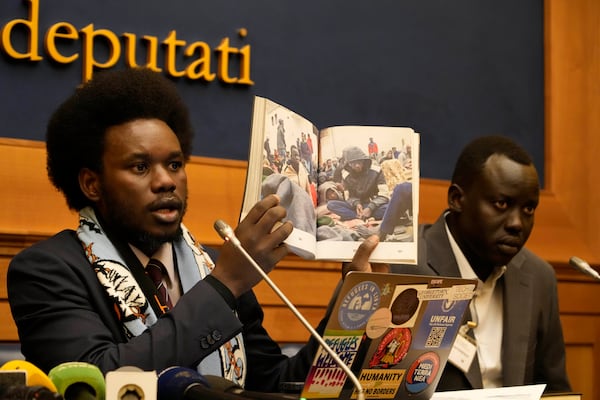 David Yambio, left, flanked by Lam Magok, both from South Sudan, shows a picture of migrants detained in a Libyan prison during a press conference at the Chamber of Deputies to testify to their experience in the Libyan prisons, in Rome, Wednesday, Jan. 29, 2025. (AP Photo/Gregorio Borgia)