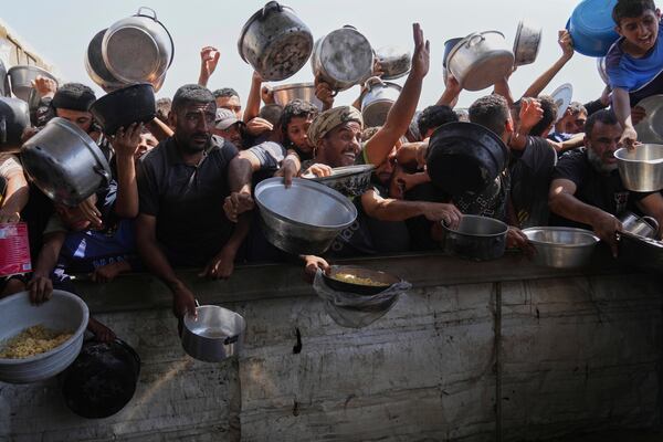 Palestinians struggle to obtain donated food at a community kitchen in Khan Younis, in the southern Gaza Strip, Friday, May 9, 2025. (AP Photo/Abdel Kareem Hana)