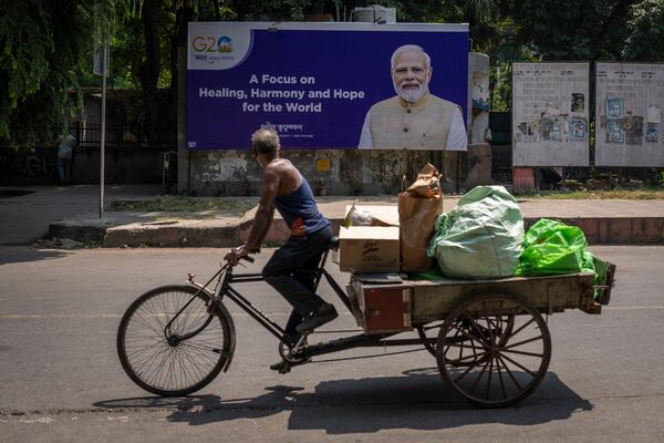 FILE - A man rides a cycle rickshaw past a billboard featuring Indian Prime Minister Narendra Modi ahead of this week's summit of the Group of 20 nations in New Delhi, India, Sept., 7, 2023. (AP Photo/Altaf Qadri, File)