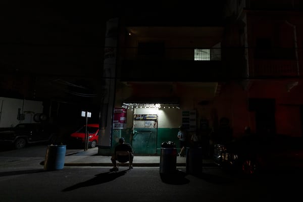 A lamp powered by a generator illuminates a sidewalk during a blackout in San Juan, Puerto Rico, after sunset Tuesday, Dec. 31, 2024. (AP Photo/Alejandro Granadillo)