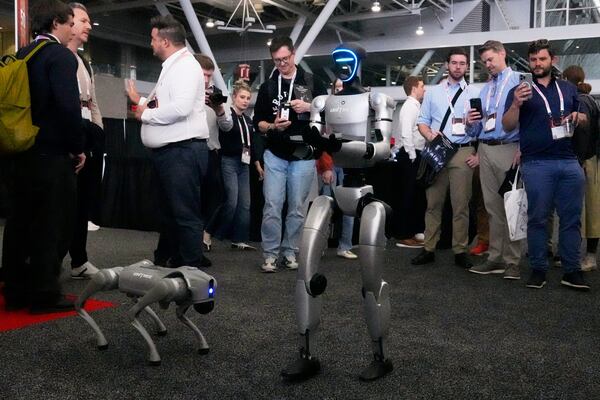 A human-like Unitree robot, right, passes out company brochures to convention guest, with a dog-like Unitree robot at its side, at the Robotics Summit & Expo, Wednesday, April 30, 2025, in Boston. (AP Photo/Charles Krupa)