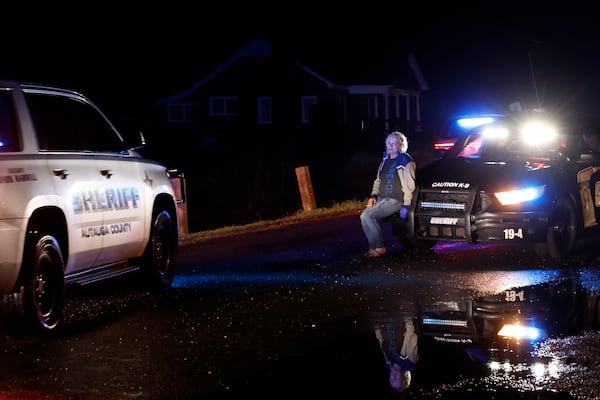 Michelle Moore rests on the bumper of a police car after she was rescued by her son who pulled her out of her trailer that was destroyed by a tornado that passed through, Saturday, March 15, 2025, in Plantersville, Ala. (AP Photo/Butch Dill)