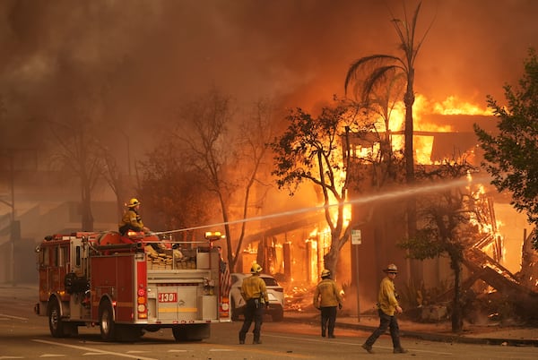 Firefighters hose down a burning structure on Lake Avenue, Wednesday, Jan. 8, 2025, in the downtown Altadena section of Pasadena, Calif. (AP Photo/Chris Pizzello)