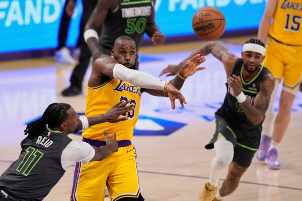 Los Angeles Lakers forward LeBron James, center, passes the ball as Minnesota Timberwolves center Naz Reid, left, and guard Nickeil Alexander-Walker defend during the second half in Game 5 of an NBA basketball first-round playoff series Wednesday, April 30, 2025, in Los Angeles. (AP Photo/Mark J. Terrill)