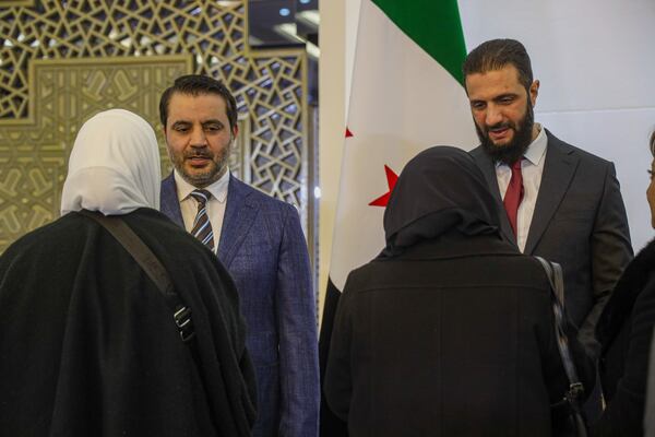 Syria's interim president Ahmad al-Sharaa, right, and interim foreign minister Asaad al-Shibani greet delegates during Syria's national dialogue conference at the People's Palace in Damascus, Syria, Tuesday Feb. 25, 2025. (AP Photo/Omar Albam)