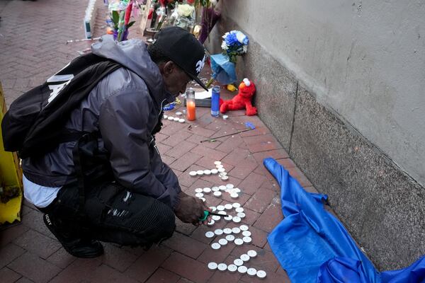 Eddie Williams lights candles for his uncle, who was killed in a deadly truck attack, at a memorial to the victims on Bourbon Street in the French Quarter, Friday, Jan. 3, 2025, in New Orleans. (AP Photo/George Walker IV)