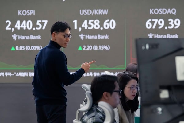 A currency trader talks to another near a screen showing the Korea Composite Stock Price Index (KOSPI), top left, and the foreign exchange rate between U.S. dollar and South Korean won, top center, at the foreign exchange dealing room of the KEB Hana Bank headquarters in Seoul, South Korea, Thursday, Dec. 26, 2024. (AP Photo/Ahn Young-joon)