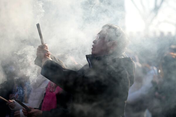 A man holding incense sticks prays on the first day of the Chinese Lunar New Year at Lama Temple in Beijing on Wednesday, Jan. 29, 2025. (AP Photo/Aaron Favila)