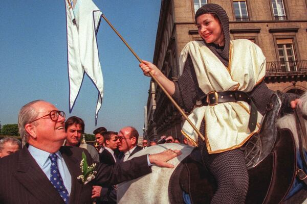 FILE - National Front party leader Jean-Marie Le Pen, left, pats a horse ridden by Francoise, posing as Joan of Arc, Thursday May 1, 1997 during a party rally. (AP Photo/Michel Lipchitz, File)