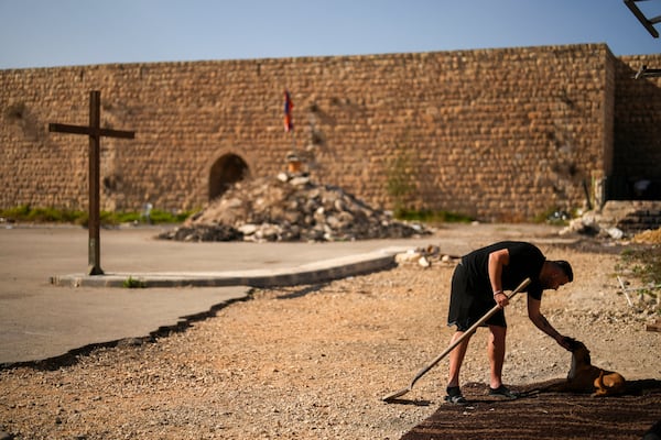 An Armenian activist pets a dog in a parking area known by locals as "Cows garden" at the Armenian quarter in Jerusalem, Thursday, Nov. 21, 2024. (AP Photo/Francisco Seco)