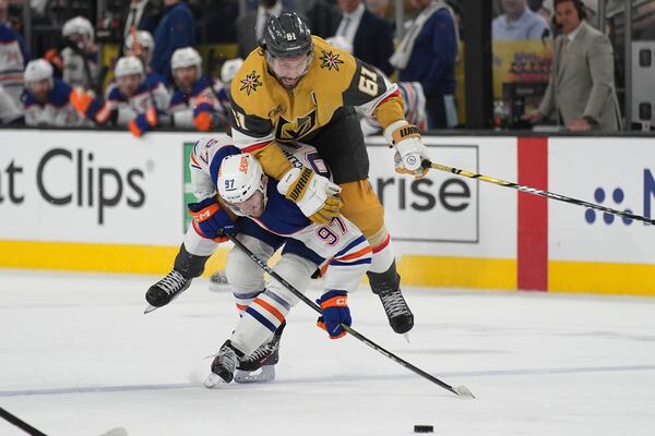 Vegas Golden Knights right wing Mark Stone (61) falls over Edmonton Oilers center Connor McDavid (97) during overtime of Game 2 of a second-round NHL hockey playoff series Thursday, May 8, 2025, in Las Vegas. (AP Photo/John Locher)