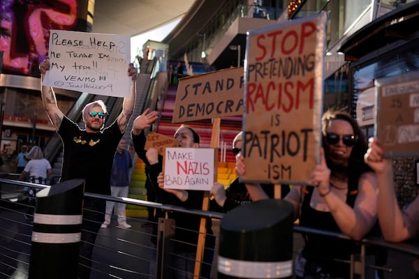 Demonstrators hold signs to protest against the Trump administration along the Las Vegas Strip, Wednesday, Feb. 5, 2025, in Las Vegas. (AP Photo/John Locher)