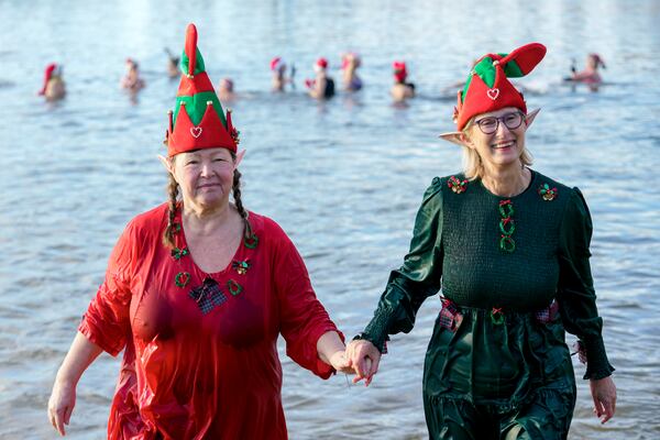 Members of the winter and ice swimming club 'Seehunde Berlin', (Berlin Seals), wearing Christmas themed hats, walk into the water during the traditional annual Christmas swim on Christmas Day, at the Oranke Lake in Berlin, Wednesday, Dec. 25, 2024. (AP Photo/Ebrahim Noroozi)