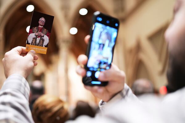 A man takes a picture of a brochure that reads "A prayer of thankfulness for the election of Pope Leo XIV" during a mass at Holy Name Cathedral in Chicago, Sunday, May 11, 2025. (AP Photo/Nam Y. Huh)