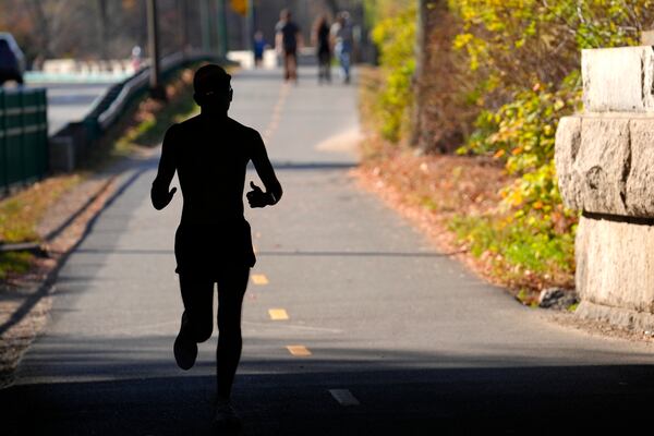 FILE - A runner appears in silhouette while running in temperatures in the 70s, Wednesday, Nov. 6, 2024, under a bridge near the Charles River, in Boston. (AP Photo/Steven Senne, File)