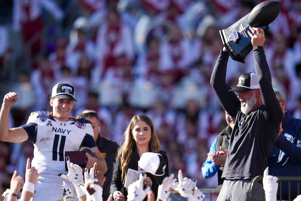 Navy head coach Brian Newberry, right, holds the Lockheed Martin Armed Forces Bowl trophy following the Armed Forces Bowl NCAA college football game against Oklahoma, Friday, Dec. 27, 2024, in Fort Worth, Texas. Navy won 21-20. (AP Photo/Julio Cortez)