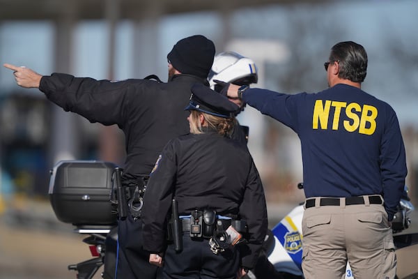 A member of the NTSB talks to Philadelphia Police officers near the scene where a small plane crashed in Philadelphia, Saturday, Feb. 1, 2025. (AP Photo/Matt Rourke)