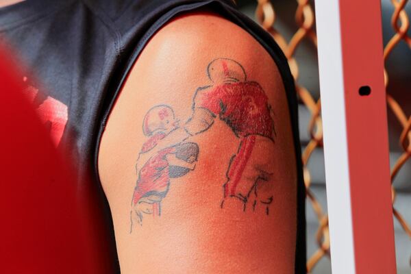 FILE - A Nebraska fan displays a tattoo rendering of cancer patient Jack Hoffman, left, who became famous when he scored a 2013 touchdown during spring scrimmage, during NCAA college football fan day in Lincoln, Neb., Aug. 2, 2013. (AP Photo/Nati Harnik, File)