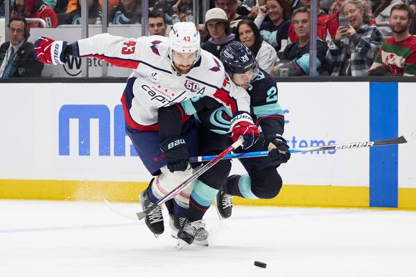 Washington Capitals right wing Tom Wilson (43) and Seattle Kraken defenseman Joshua Mahura (28) collide as they go for the puck during the third period of an NHL hockey game, Thursday, Jan. 23, 2025, in Seattle. (AP Photo/John Froschauer)