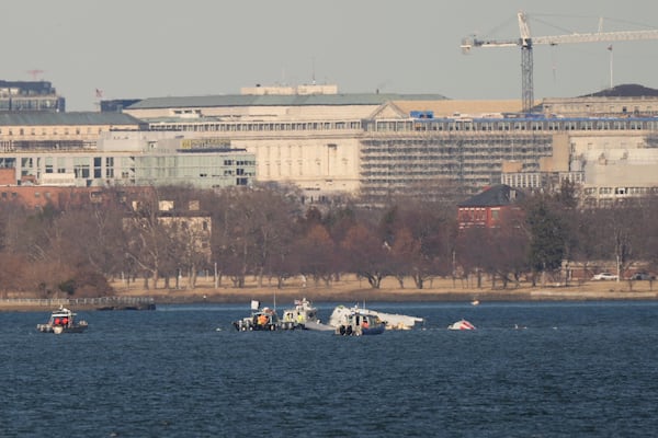 Search and rescue boats work on the Potomac river, Saturday, Feb. 1, 2025, in Arlington, Va., near the wreckage of an American Airlines jet that collided with a Black Hawk helicopter, as seen from Alexandria, Va. (AP Photo/Carolyn Kaster)