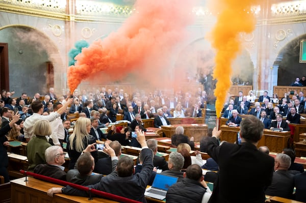 MPs of Momentum protest with flares during the plenary session of the Hungarian parliament in Budapest, Hungary, Tuesday, March 18, 2025. (Boglarka Bodnar/MTI via AP)