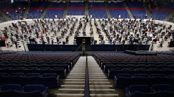 FILE - Members of the New Hampshire House of Representatives stand at the start of their session in Durham, N.H. on at the Whittemore Center at the University of New Hampshire, June 11, 2020. The Legislature, which suspended its work in March because of the COVID-19 virus outbreak, gathered at the arena for the first House session held outside the Statehouse since the Civil War. (AP Photo/Charles Krupa, File)