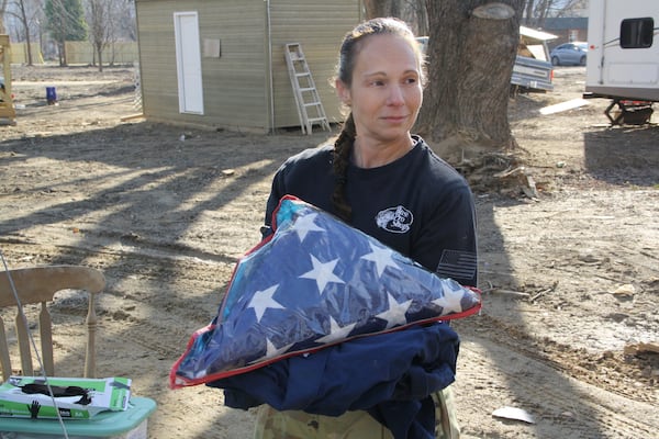 Jill Holtz somberly holds a burial flag she pulled from the mud — one of the most emotional moments in her searches, she said — andis waiting to return to a family she contacted on Thursday, Feb. 6, 2025, in Swannanoa, N.C. (AP Photo/Makiya Seminera)