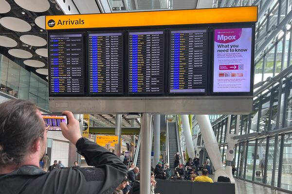 A man takes a photo of the flight information display in the arrivals hall at Heathrow Terminal 5 in London, Saturday March 22, 2025, after flights resumed at the airport. (Maja Smiejkowska/PA via AP)