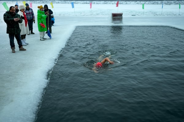 Residents watch a woman swim in a pool carved from ice on the frozen Songhua river in Harbin in northeastern China's Heilongjiang province, Tuesday, Jan. 7, 2025. (AP Photo/Andy Wong)