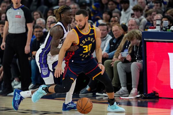 Golden State Warriors guard Stephen Curry (30) moves the ball while defended by Sacramento Kings guard Keon Ellis during the first half of an NBA basketball game Thursday, March 13, 2025, in San Francisco. (AP Photo/Godofredo A. Vásquez)