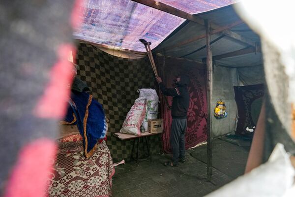 A man removes water from the fabric roof of a makeshift tent following overnight rainfall at the refugee tent camp for displaced Palestinians in Deir al-Balah, central Gaza Strip, Tuesday, Dec. 31, 2024. (AP Photo/Abdel Kareem Hana)