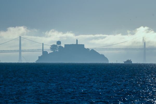 FILE - A boat makes its way toward Alcatraz Island with the San Francisco-Oakland Bay Bridge in the background in this view from Sausalito, Calif., Dec. 13, 2023. (AP Photo/Eric Risberg, File)