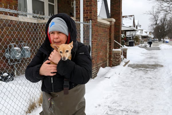 Lisa Muscat carries her dog Zoey to safety after a water main break in Detroit caused massive flooding, triggering evacuations, Monday, Feb. 17, 2025. (Andy Morrison/Detroit News via AP)