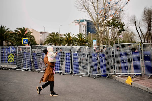 A woman walks past police cordons blocking the roads leading to the Vatan Security Department, where Istanbul Mayor Ekrem Imamoglu is expected to be taken following his arrest in Istanbul, Turkey, Wednesday, March 19, 2025. (AP Photo/Emrah Gurel)