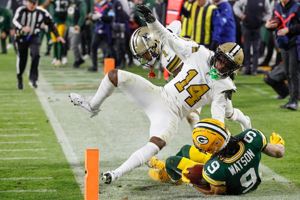 Green Bay Packers wide receiver Christian Watson (9) is knocked out of bounds by New Orleans Saints cornerback Kool-Aid McKinstry (14) during the first half of an NFL football game, Monday, Dec. 23, 2024, in Green Bay, Wis. (AP Photo/Mike Roemer)