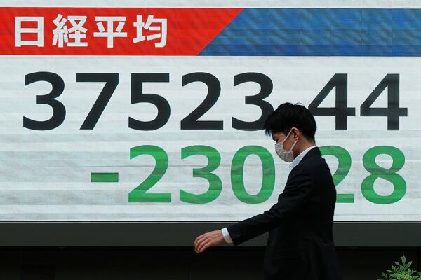 A person walks in front of an electronic stock board showing Japan's Nikkei index at a securities firm Monday, May 19, 2025, in Tokyo. (AP Photo/Eugene Hoshiko)