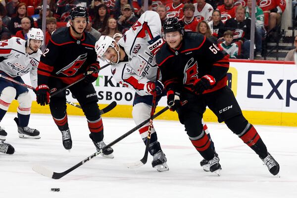 Carolina Hurricanes' Eric Robinson (50) battles for the puck with Washington Capitals' Nic Dowd (26) with Hurricanes' Jesperi Kotkaniemi (82) nearby during the first period of Game 4 of a second-round NHL hockey playoff series in Raleigh, N.C., Monday, May 12, 2025. (AP Photo/Karl DeBlaker)