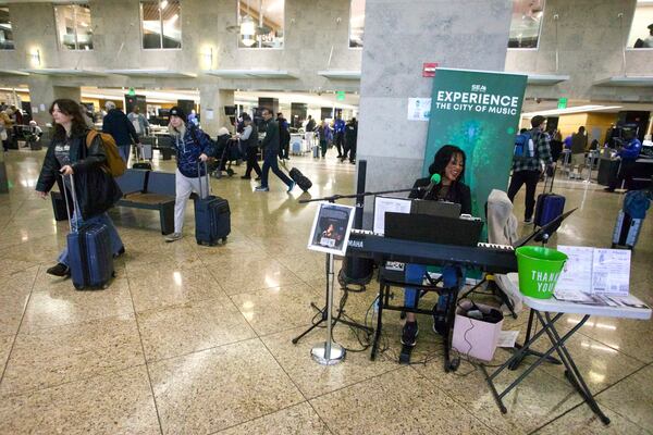 Roz McCommon performs amid travelers at Seattle-Tacoma International Airport on November 26, 2024, in SeaTac, Wash. (AP Photo/Manual Valdes)