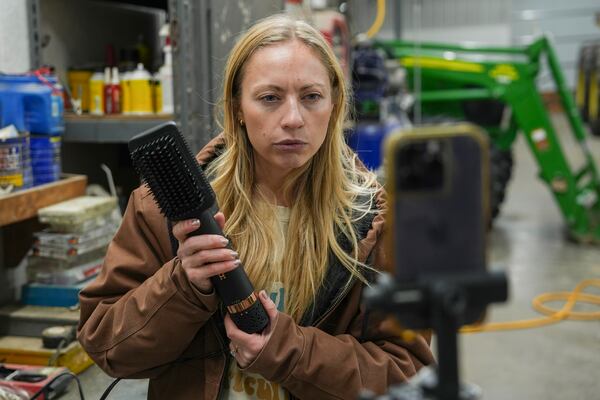 Zoe Kent uses a hair brush as a prop while filming a social media video, Monday, Jan. 20, 2025, at her farm in Bucyrus, Ohio. (AP Photo/Joshua A. Bickel)