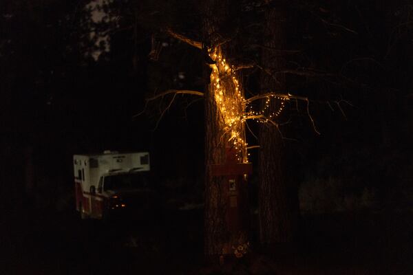 A string of lights hangs on a tree above a memorial at a homeless encampment in Deschutes National Forest Wednesday, April 30, 2025 near Bend, Ore. (AP Photo/Jenny Kane)