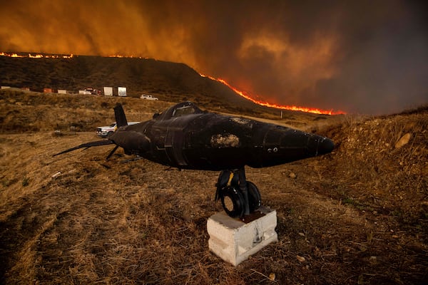 A charred replica of an aircraft sits in a paintball course as flames caused by the Hughes Fire pass along in Castaic, Calf., Wednesday, Jan. 22, 2025. (AP Photo/Ethan Swope)